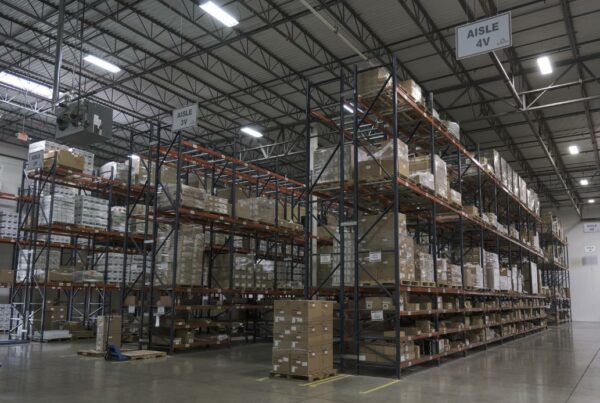Efficient warehouse with organized product on shelves and hanging signs.